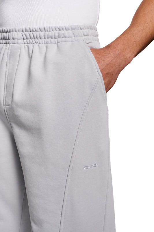 Person trägt CC Core Sweatpants Gray mit elastischem Bund und Kordelzug, Rippbündchen, Teilungsnähten und regulärer Passform. Unisex-Design für OLAKALA.
