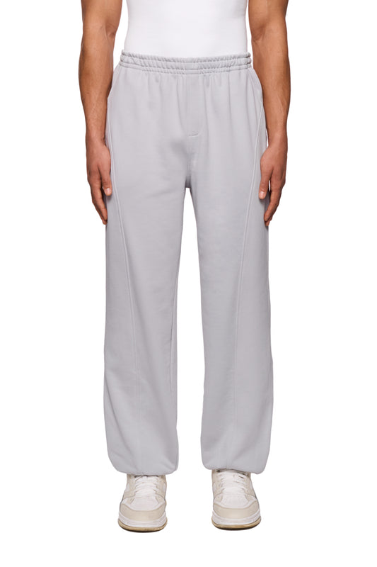Person in CC Core Sweatpants Grau mit elastischem Bund und Kordelzug, zeigt strapazierfähige Mischfaser und elegante Teilungsnähte, unisex, reguläre Passform.