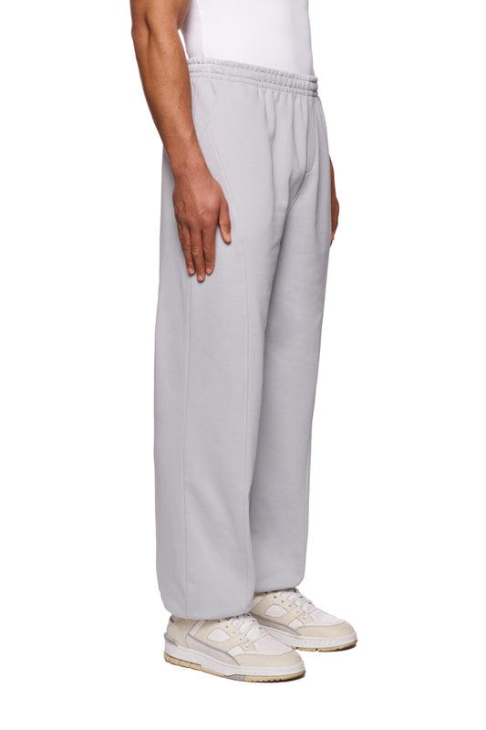 Person trägt die CC Core Sweatpants Gray mit elastischem Bund und Kordelzug, sichtbarem Rippabschluss und Teilungsnähten, ideal für einen eleganten, unisexen Look.