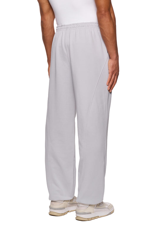 Person trägt CC Core Sweatpants Gray mit elastischem Bund und Kordelzug, kombiniert mit weißen Sneakern, betont durch Rippbündchen und Teilungsnähte für eleganten Look.