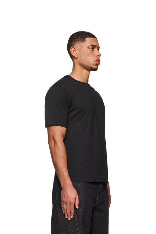 Mann im CC Core T-Shirt Black mit gesticktem OLAKALA-Icon auf der Brust, reguläre Passform, unisex.