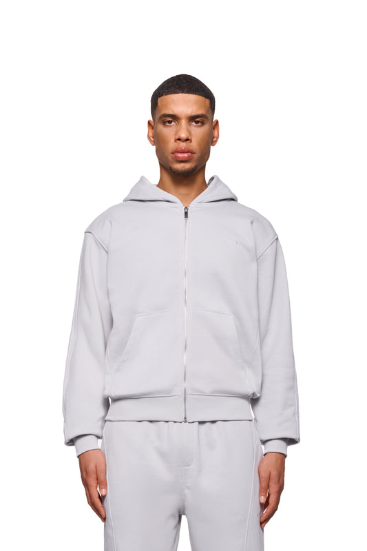 Mann trägt CC Core Zip Hoodie Gray mit Rippbündchen, Kängurutasche und verlegten Nähten für Komfort, geeignet für den offiziellen OLAKALA® Onlineshop.