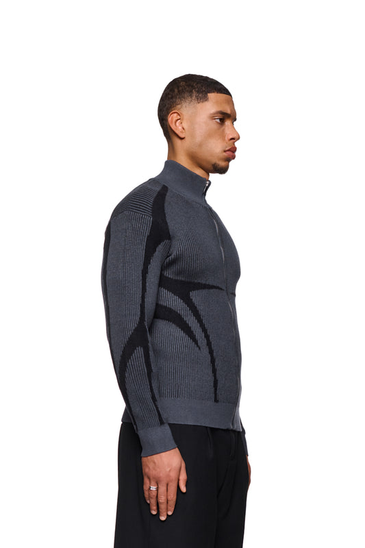 Mann trägt Luminous Zip Jacket Gray mit hohem Kragen, gestricktem Muster und elastischen Bündchen. Reguläre Passform, unisex.