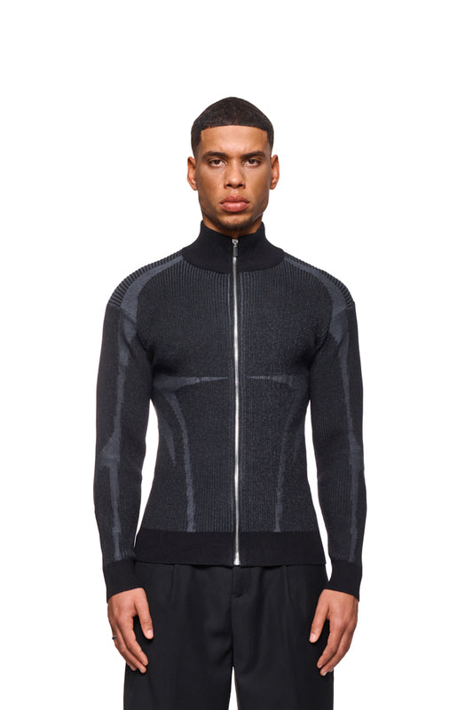 Ein Mann trägt eine Luminous Zip Jacket Black mit hohem Kragen und gestricktem Muster. Die Jacke hat elastische Bündchen und reguläre Passform.