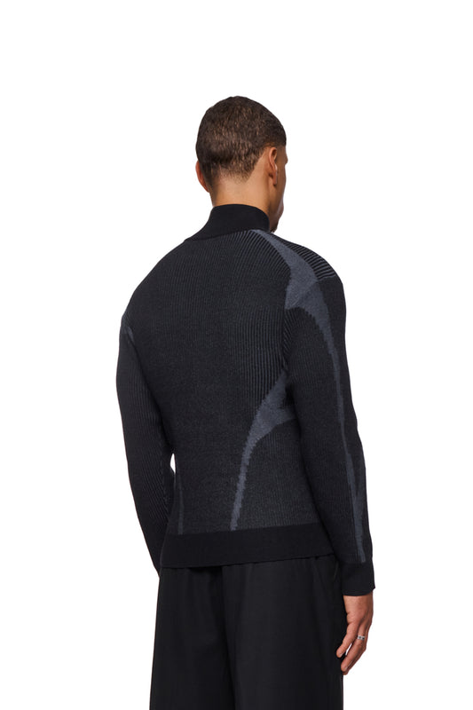 Mann trägt Luminous Zip Jacket Black mit hohem Kragen, elastischen Bündchen, gestricktem Muster, regulärer Passform. Unisex-Design von OLAKALA.