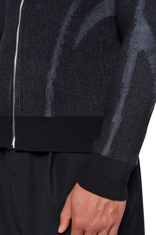 Nahaufnahme des Arms einer Person in einem Luminous Zip Jacket Black mit hohem Kragen und gestricktem Muster, das eine reguläre Passform bietet.