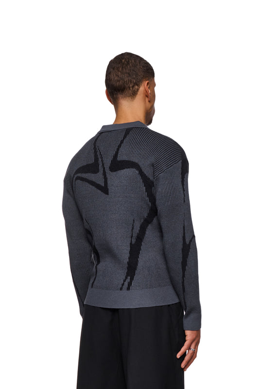 Man wears gray Luminous polo with knitted pattern, elastic cuffs and loose fit. Unisex design, presented by OLAKALA.