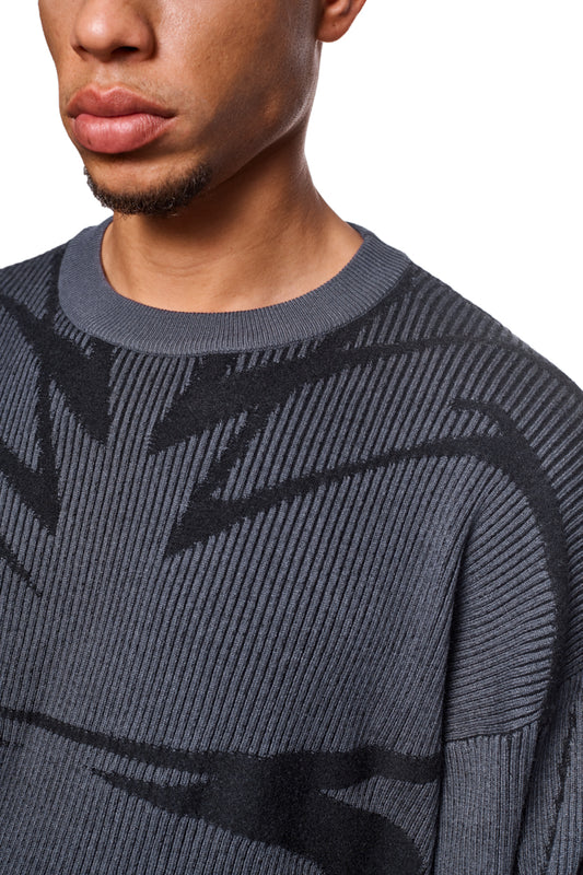 Close-up of a man wearing the Luminous Sweater Gray, which features knitted cuffs and a loose, unisex design.