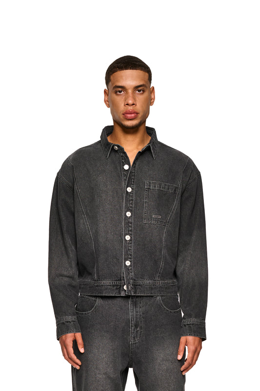 Nahaufnahme eines Mannes, der das 0asis Denim Overshirt Black trägt, zeigt Details wie Knopfleiste, Brusttaschen und OLAKALA-Patch auf der Rückseite.