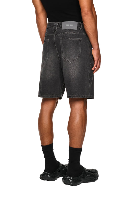 Nahaufnahme von schwarzen Socken in schwarzen Schuhen, getragen mit 0asis Denim Shorts Black, die mit fünf Taschen und OLAKALA-Details ausgestattet sind.