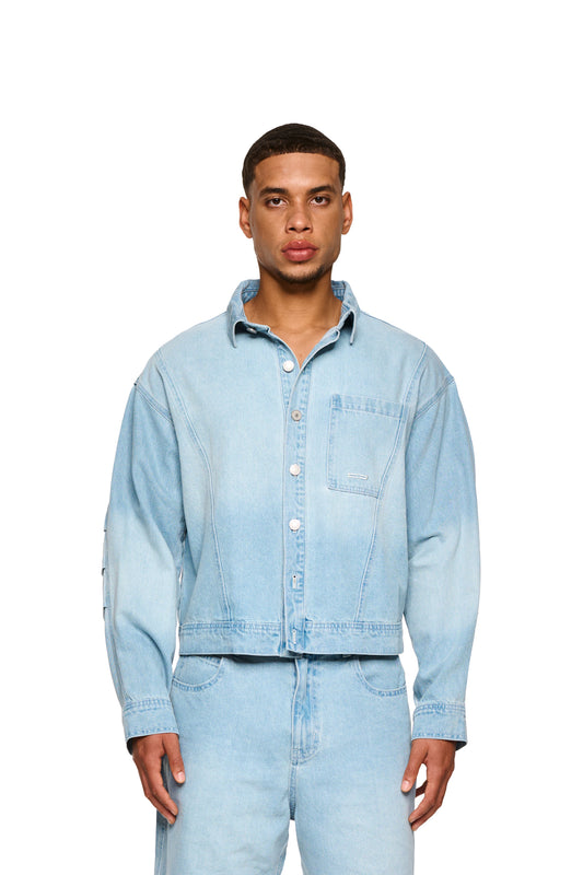 Nahaufnahme eines Mannes, der ein 0asis Denim Overshirt Blue trägt, mit sichtbarer Knopfleiste und aufgesetzter Brusttasche mit Logo-Stickerei.