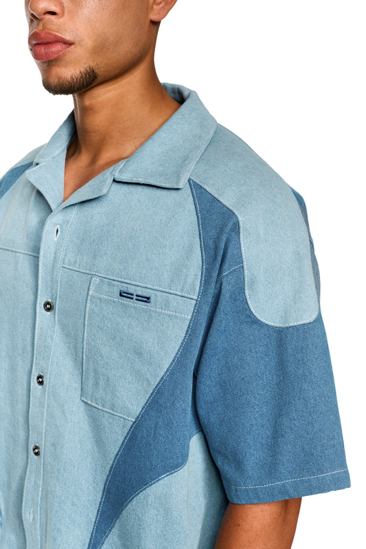 Nahaufnahme eines Mannes, der das Echoes Denim Icon Shirt Blue trägt, mit kubanischem Kragen, Knopfleiste und kontrastierenden Teilungsnähten.