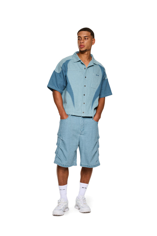 Mann in Echoes Denim Icon Shirt Blau mit kubanischem Kragen und Brusttasche, steht und präsentiert das Hemd aus leichtem, robustem Köper-Gewebe.