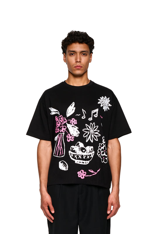 Mann trägt Crayon T-Shirt Oversized Black. Nahaufnahme zeigt Details des Shirts, passend zum urbanen Stil des offiziellen OLAKALA® Onlineshops.