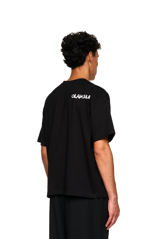 Mann von hinten im Crayon T-Shirt Oversized Black, schwarzes Shirt mit weißem Text, betont lässigen Stil. Perfekt für den OLAKALA® Onlineshop.