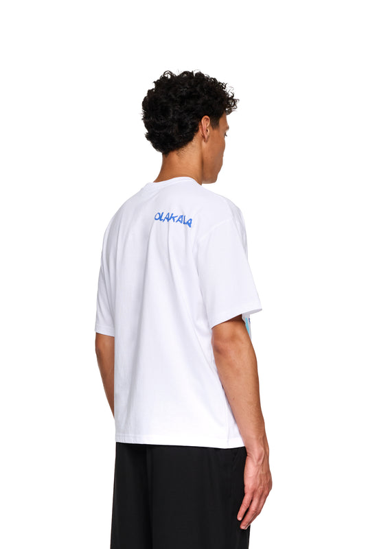 Ein Mann trägt ein übergroßes, weißes Crayon T-Shirt von OLAKALA, sichtbar von hinten, kombiniert mit einer Nahaufnahme schwarzer Hosen.