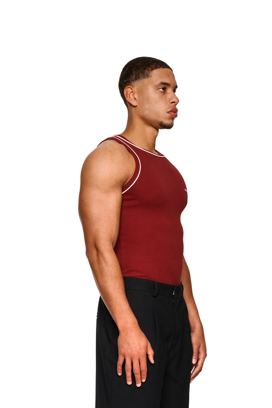 Hand in Nahaufnahme, die das Contrast Tanktop Burgundy mit gesticktem OLAKALA Icon auf der Brust zeigt, betont die enge Passform und Unisex-Design.