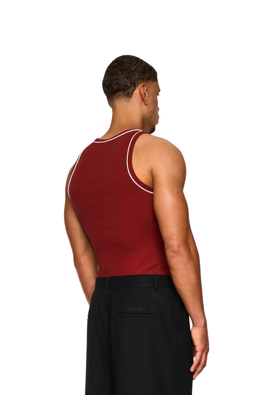 Mann im roten Contrast Tanktop Burgundy mit gesticktem OLAKALA-Icon auf der Brust, zeigt elastischen Ripp-Stoff und enge Passform.