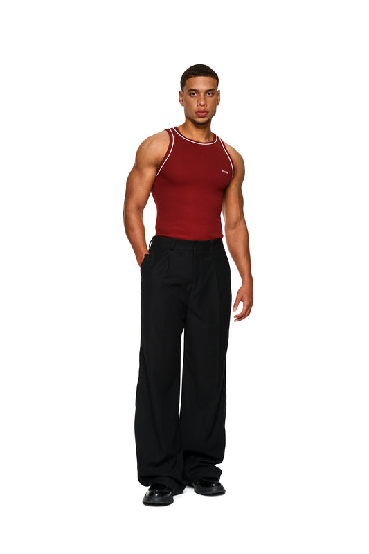 Nahaufnahme eines Mannes im roten Tanktop mit engem Schnitt und gesticktem OLAKALA-Icon auf der Brust.