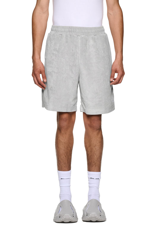 Nahaufnahme von Terry Shorts Gray mit elastischem Bund, Kordelzug und Logo-Stickerei auf dem linken Bein, präsentiert an einer stehenden Person.