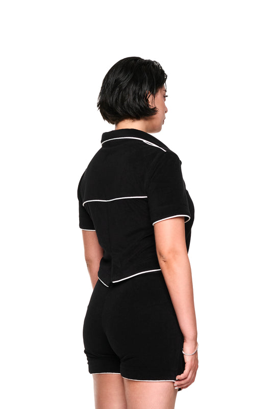 Nahaufnahme eines weichen, strukturierten Terry Shirt Black Cropped mit 3D-Monogramm-Effekt, kontrastierenden Paspelierungen und Logo-Stickerei auf der linken Brust.