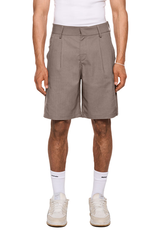 Linen Shorts Beige mit Bundfalten, französischen Taschen und asymmetrischem Eingriff. Reguläre Passform, unisex, mit Schlitzen an den Hosenbeinseiten.