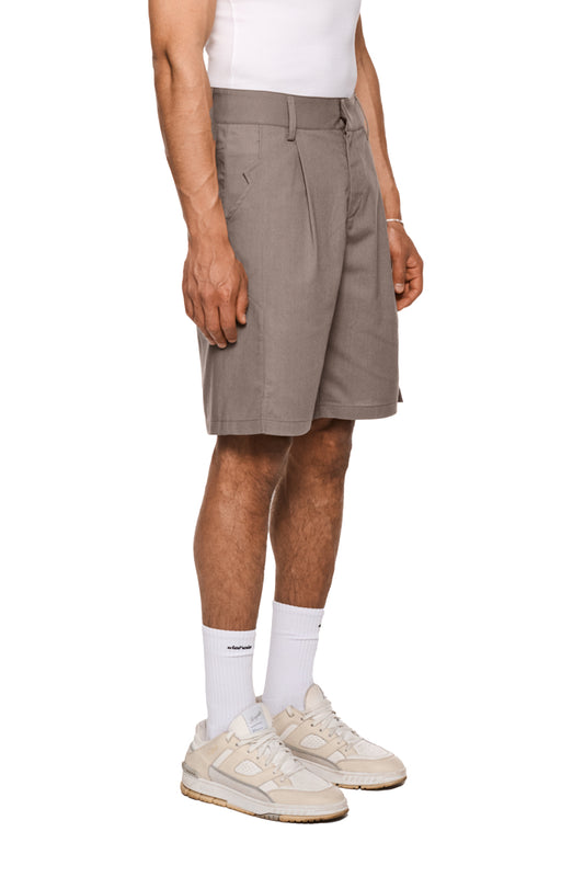 Linen Shorts Beige mit Bundfalten, französischen Taschen, asymmetrischem Eingriff, Leistentaschen hinten und Schlitzen an den Hosenbeinen. Unisex, reguläre Passform.