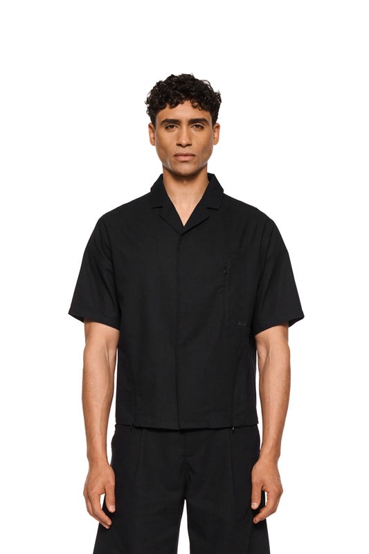 Short sleeve linen shirt black with safari collar, breathable fabric, side slits, zipper details and chest pocket with logo embroidery. Unisex, regular fit.