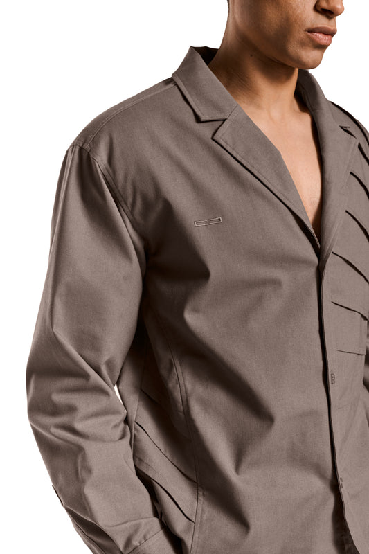Sun Linen blazer with asymmetric safari collar, removable shoulder padding and shirt button placket, unisex design with sophisticated pleat and cuff details.