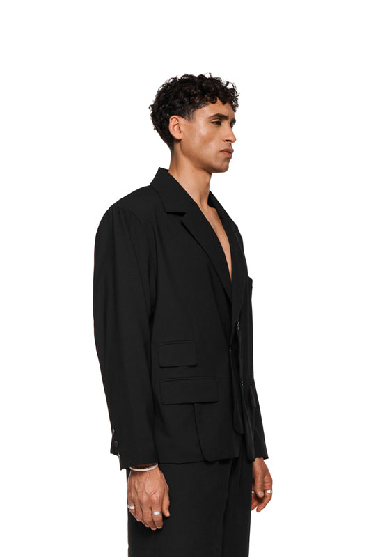 Layered blazer with asymmetric cut, double-layered left side, removable shoulder padding, asymmetric lapel collar and versatile flap pockets, matching the unisex OLAKALA collection.