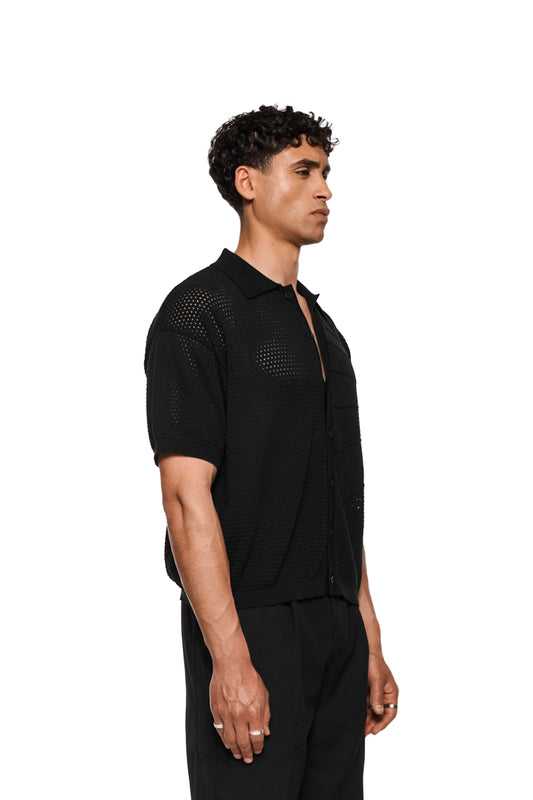 Sun Knit Shirt Black mit feinem Lochstrickmuster, Sonnendetail, doppellagigem Kragen, Knopfleiste und lockerer Passform. Perfekt für warme Sommertage. Unisex-Design.