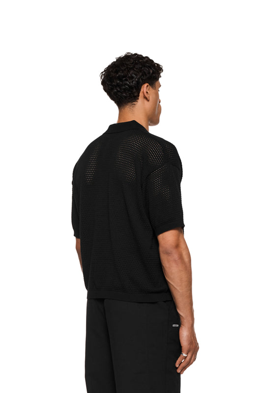 Sun Knit Shirt Black mit feinem Lochstrickmuster, Sonnendetail, doppellagigem Kragen, Knopfleiste und lockerer Unisex-Passform, ideal für warme Sommertage.