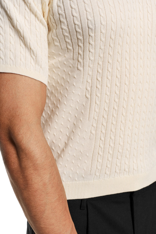 Schmal geschnittenes Poloshirt mit Zopfmuster und doppellagigem Kragen. Unisex-Design, enganliegend, ohne Knopfleiste. Produkt: Fitted Knit Polo Creme.