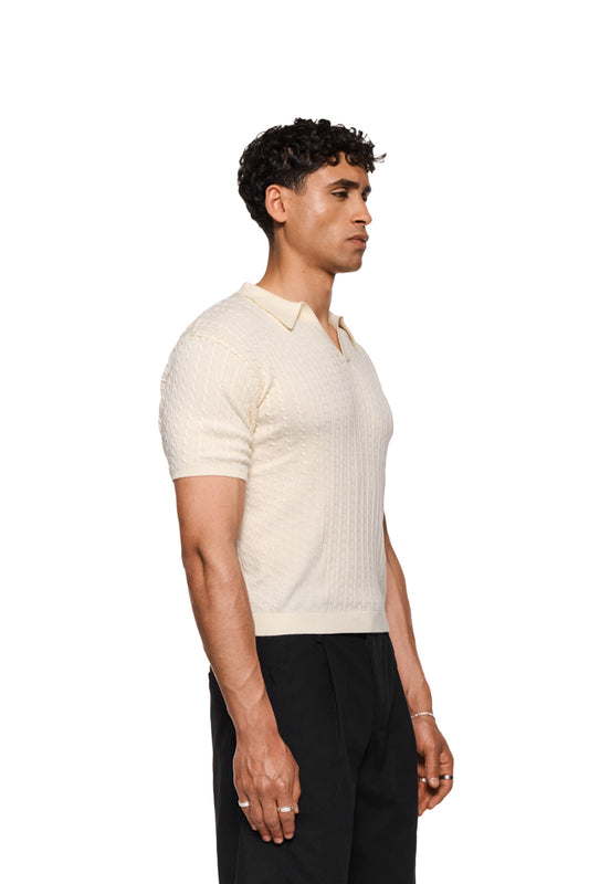 Schmal geschnittenes Poloshirt im Zopfmuster-Strick, doppellagiger Kragen, ohne Knopfleiste, eng anliegend, unisex, präsentiert von OLAKALA als Fitted Knit Polo Creme.