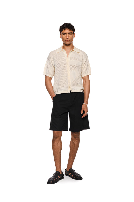 Sun Knit Shirt Creme mit feinem Lochstrickmuster, Sonnendetail, doppellagigem Kragen, Knopfleiste vorn und lockerer, unisex Passform. Perfekt für warme Sommertage.