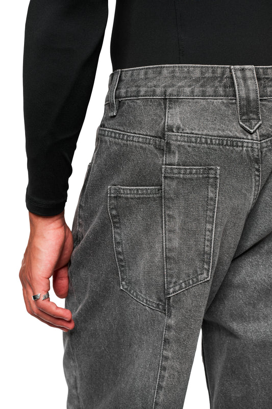 Person trägt CC Core Denim Pants Washed Gray mit lockerem Schnitt und großer Oberschenkeltasche, kombiniert mit einem schwarzen Langarmtop und silbernen Ringen an der Hand.