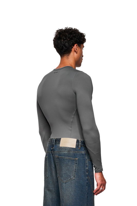 Person von hinten in CC Core Slim Fit Longsleeve Gray, schmale Passform, aus weichem Stretch-Material, kombiniert mit locker sitzenden blauen Jeans.