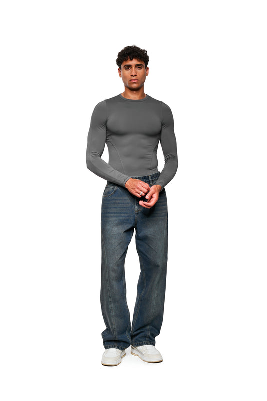 Männermodell trägt CC Core Denim Pants Tinted Indio, locker geschnittene Jeans mit 5-Pocket-Stil, versetzte Seitennaht und asymmetrische Gesäßtasche, präsentiert von OLAKALA.