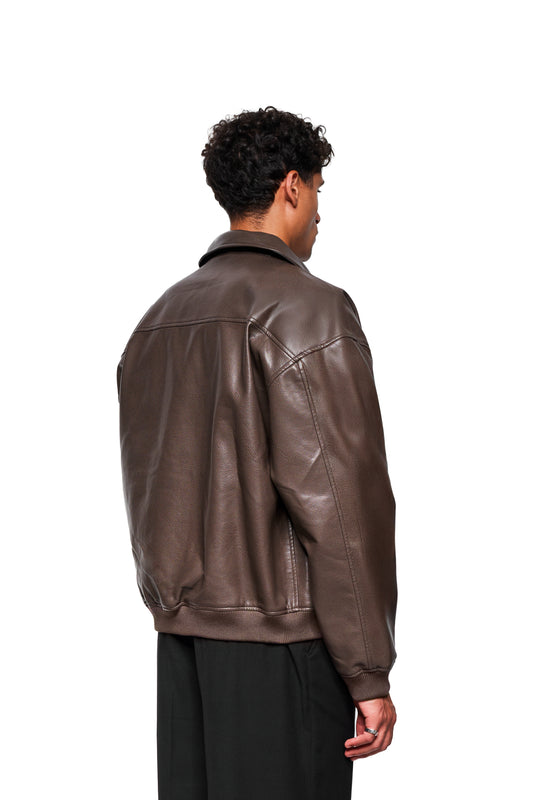 Person von hinten in CC Leather Jacket Icon Brown aus veganem Lederimitat mit überschnittener Schulter, geripptem Saum, Druckknopftaschen und gesticktem OLAKALA-Logo.