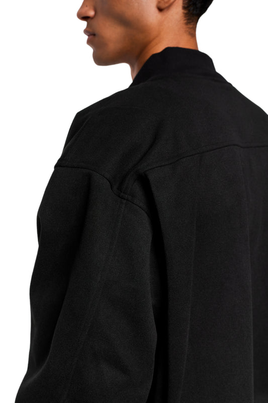 Exquisite black bomber jacket with ribbed stand-up collar, breast pocket and embroidered OLAKALA icon. Visible back seams and slightly cropped, loose fit.