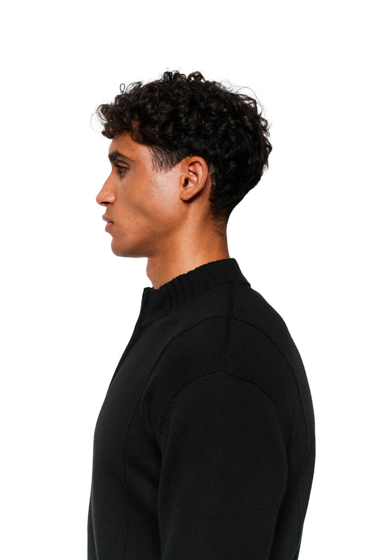 Junger Mann im Profil in einem schwarzen Sommerstrickjacke mit Rippenmuster und Stehkragen aus weichem Baumwollstrick.