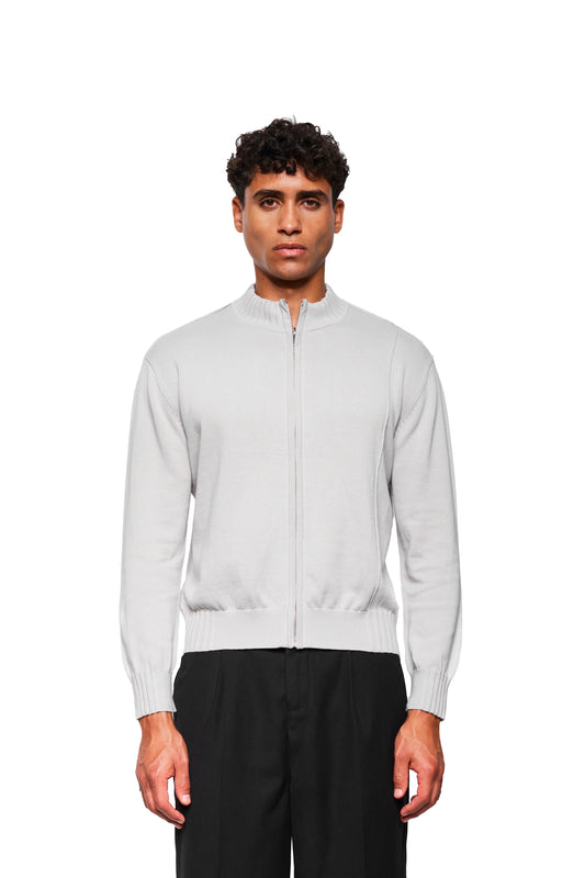 Männliches Model trägt die Summer Knit Jacket Light Gray, eine leichte Strickjacke mit asymmetrischer Vorderseite und strukturiertem Rippenmuster, kombiniert mit schwarzen Hosen.