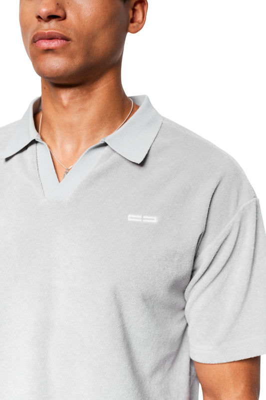 Mann trägt ein Terry Polo Gray aus weichem Frotteematerial mit gesticktem Logo auf der Brust, kombiniert mit einer silbernen Kette.