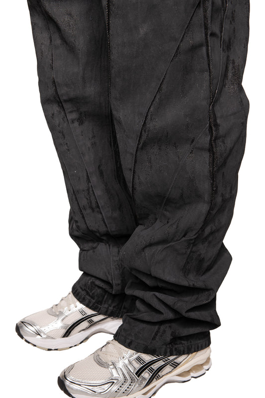 Legs visible in loose-fitting CI Coated Denim Pants Regular with destroyed all-over print and dividing seams, combined with silver and white sneakers.