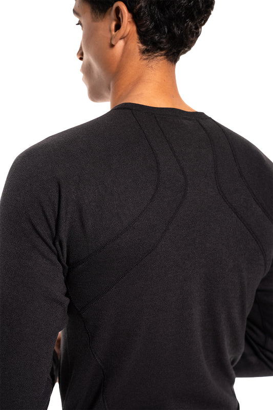Person von hinten in einem eng anliegenden Terra Base Layer Longsleeve Black, das Naht- und Paneeldetails betont, ideal als funktionale Basis im Schichtsystem.