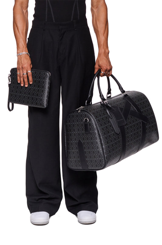 Person hält CC XL Weekender Bag Black mit abnehmbarem Schulterriemen und OLAKALA Metallreißverschluss; enthält abnehmbare Key Pouch und Pochette Bag.