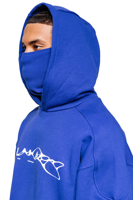 Person with Synergy Mask Hoodie Blue, attached hood, integrated mask, white Synergy graphic on the chest, oversized fit, ribbed cuffs, elastic hem, unisex.