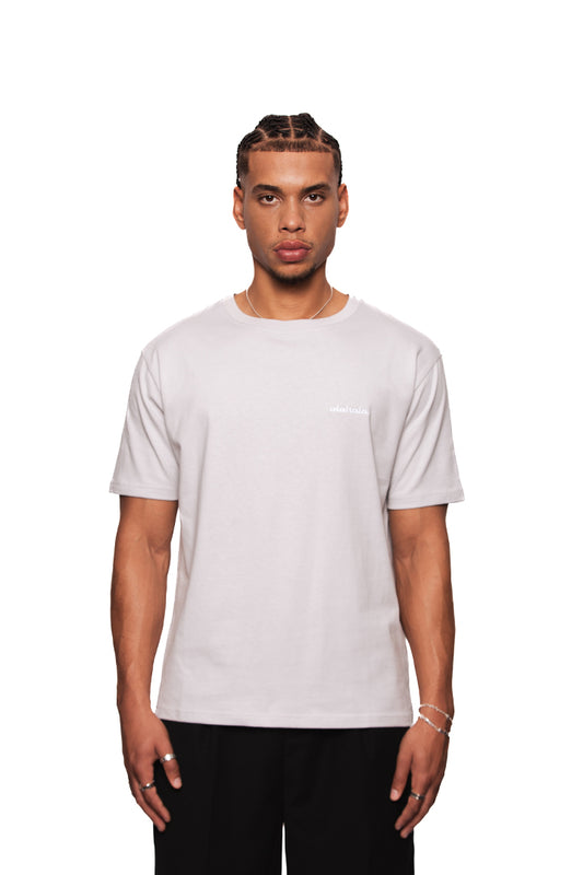 Junger Mann im NC T-Shirt Gray Regular mit OLA KALA Logo links, zeigt Schmuck an Händen.