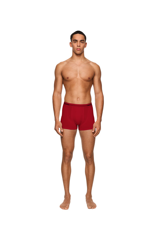 Ein Mann trägt OLAKALA Boxershorts im 3er Pack mit elastischem Bund und eingewebtem Logo, präsentiert in einer roten Geschenkbox.