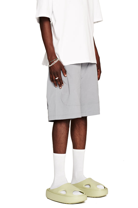 Man wears the Terra Track Shorts with drawstring, zipper pockets, dividing seams and embroidered E logo, combined with white socks and sandals.